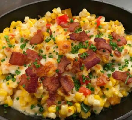 A skillet filled with macaroni and cheese, corn, diced red peppers, chopped chives, and crispy bacon pieces on top—perfectly prepared using a sub zero appliance in a luxury kitchen.