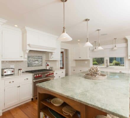 brick titled kitchen with wood floors and a off green counter top island.