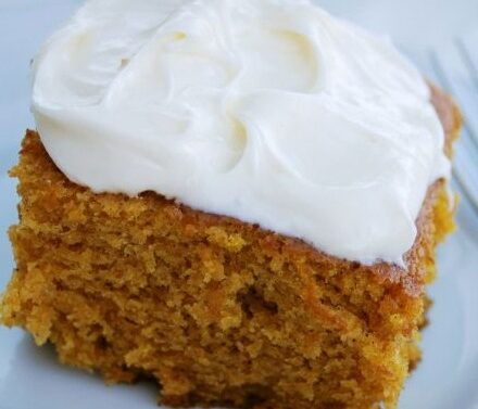 A slice of moist, brown cake with white frosting on top, served on a white plate with a fork beside it, reminiscent of desserts crafted in a luxury kitchen appliance display at a modern kitchen showroom.