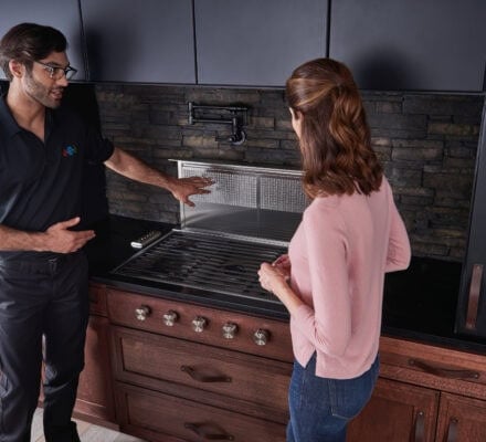 A man and woman standing in front of a Wolf cooktop