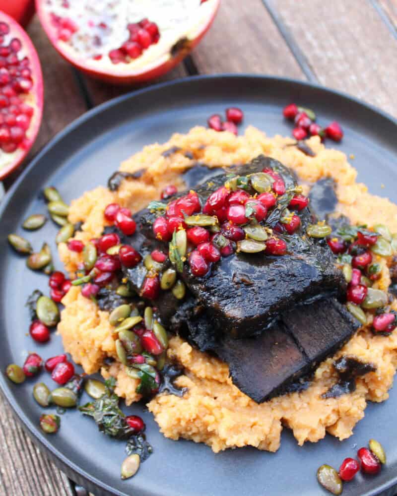 A plate of food with fruit alongside Black Cocoa & Espresso Braised Short Ribs.