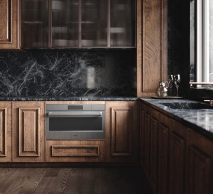 Modern kitchen with dark wood cabinets, black marble countertops and backsplash, a built-in steam convection oven, and glass-front upper cabinets next to a large window.