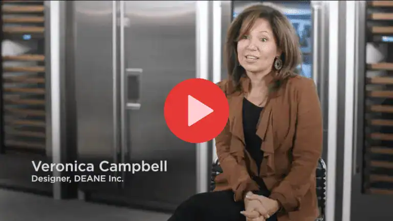 A woman sits in front of Clarke stainless steel appliances, with the name "Veronica Campbell, Designer, DEANE Inc." displayed at the bottom and a play button overlay in the center.