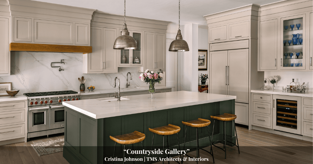 Spacious kitchen with white cabinetry, marble backsplash, green island with four wooden stools, pendant lights, and built-in appliances; flowers arranged on the island add charm to this home inspired by rich Clarke History.
