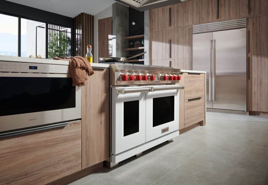 Modern kitchen with wooden cabinets, stainless steel appliances, a double oven with red knobs, and light gray tile flooring—perfect inspiration for your kitchen planner guide.