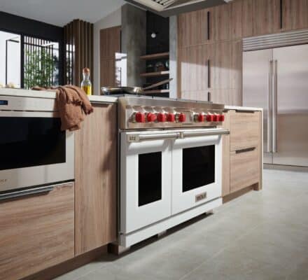 Modern kitchen with wooden cabinets, stainless steel appliances, a double oven with red knobs, and light gray tile flooring—perfect inspiration for your kitchen planner guide.